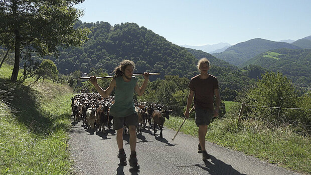 Deux bergers du documentaire La réponse des bergers marchent devant un troupeau de chèvres en montagne